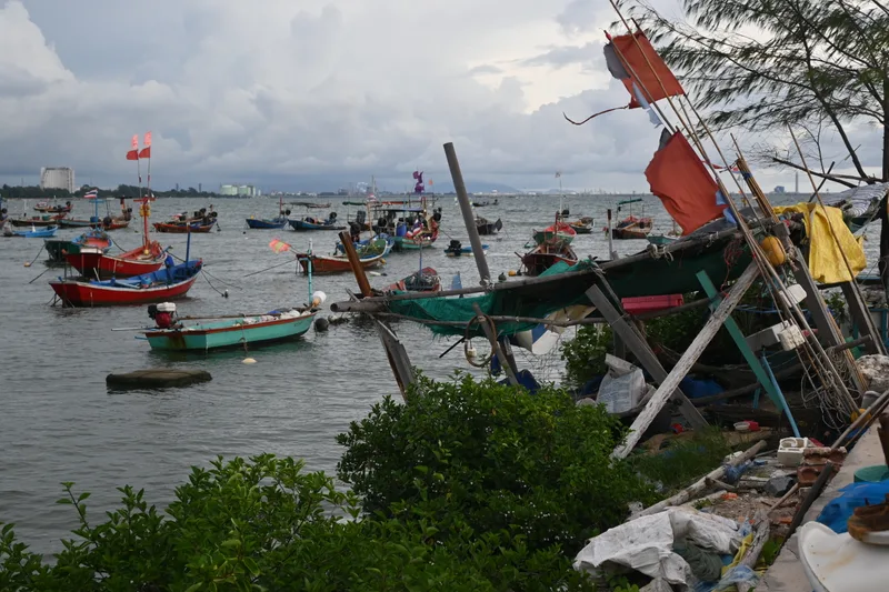 Fishing boats in a working harbor with gear and nets along the shore