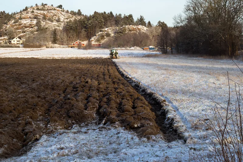 A tractor paused in a partially plowed farm field