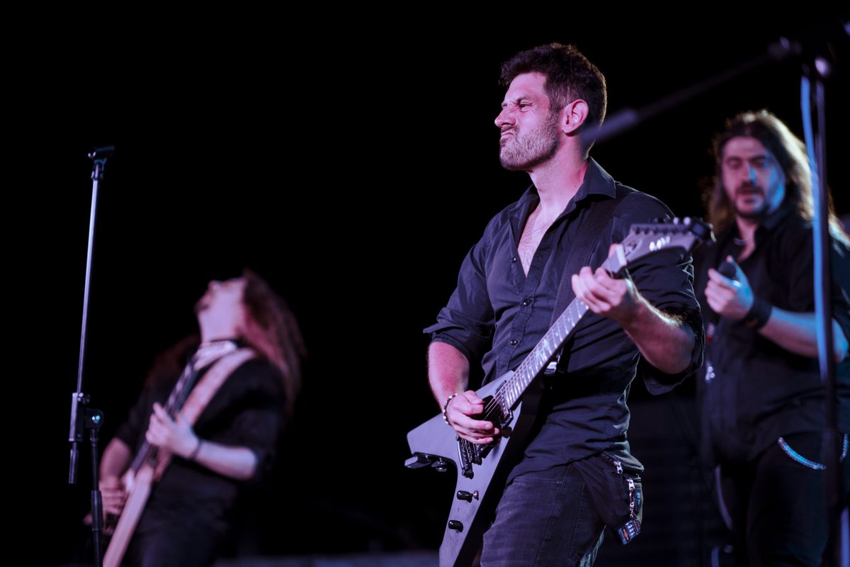 A band performing on stage at an outdoor night concert