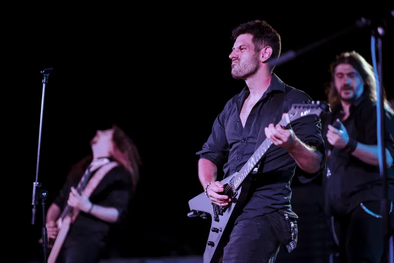 A band performing on stage at an outdoor night concert