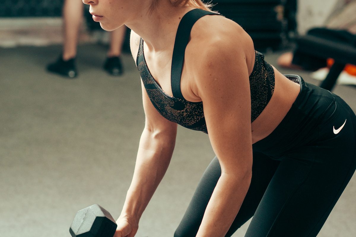 A trainer lifting dumbbells in a modern gym