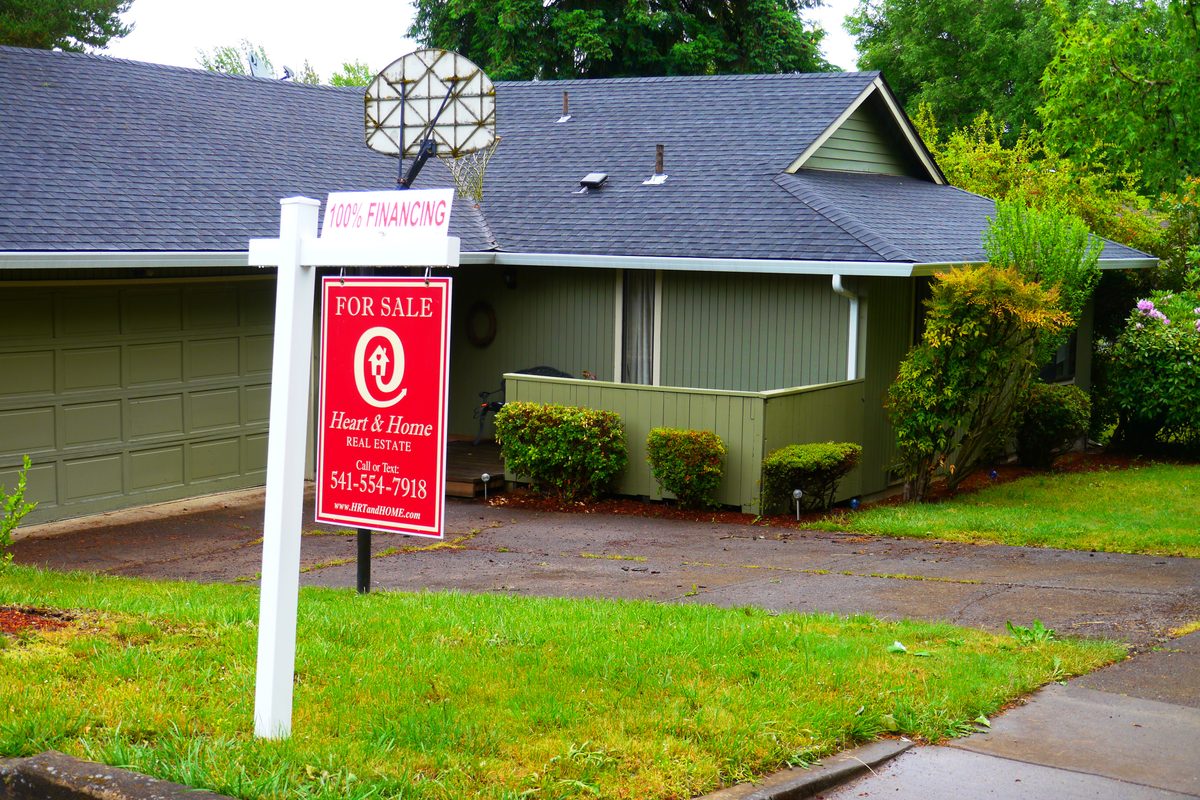 A residential for-sale sign in front of a listed home