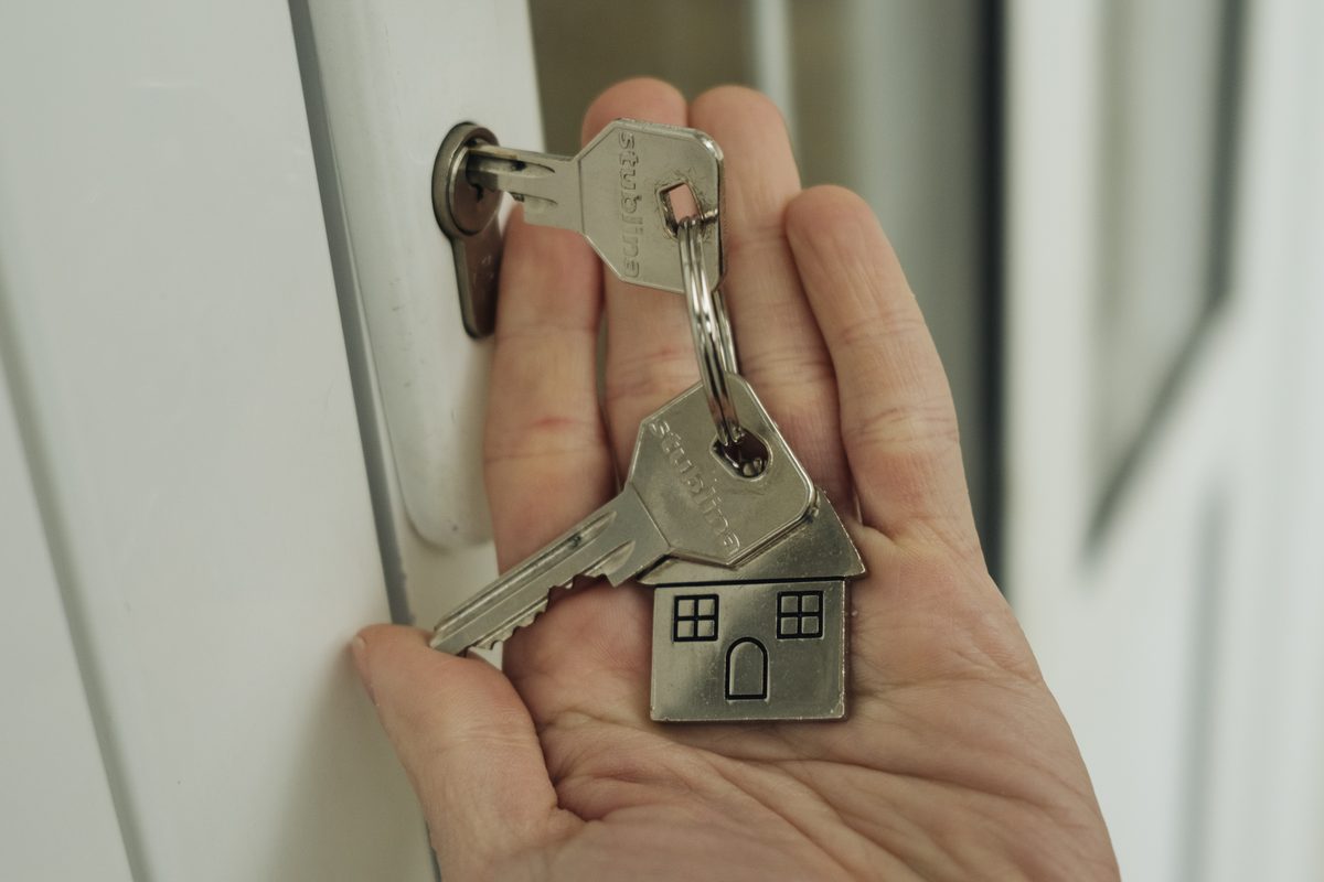 A hand holding house keys in front of a door lock