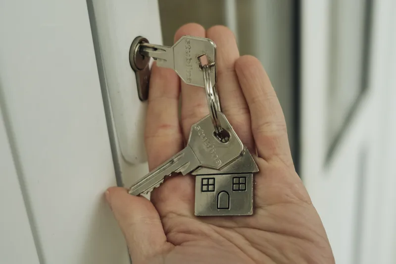 A hand holding house keys in front of a door lock