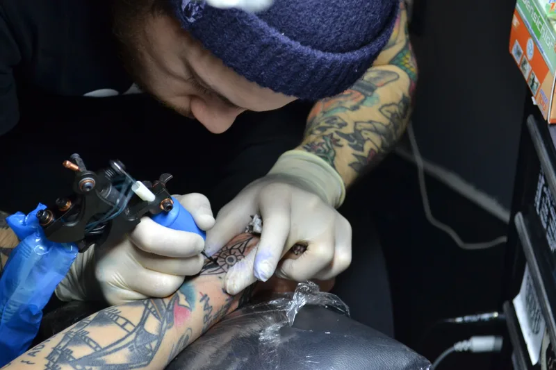 A tattoo artist working on a client in a studio